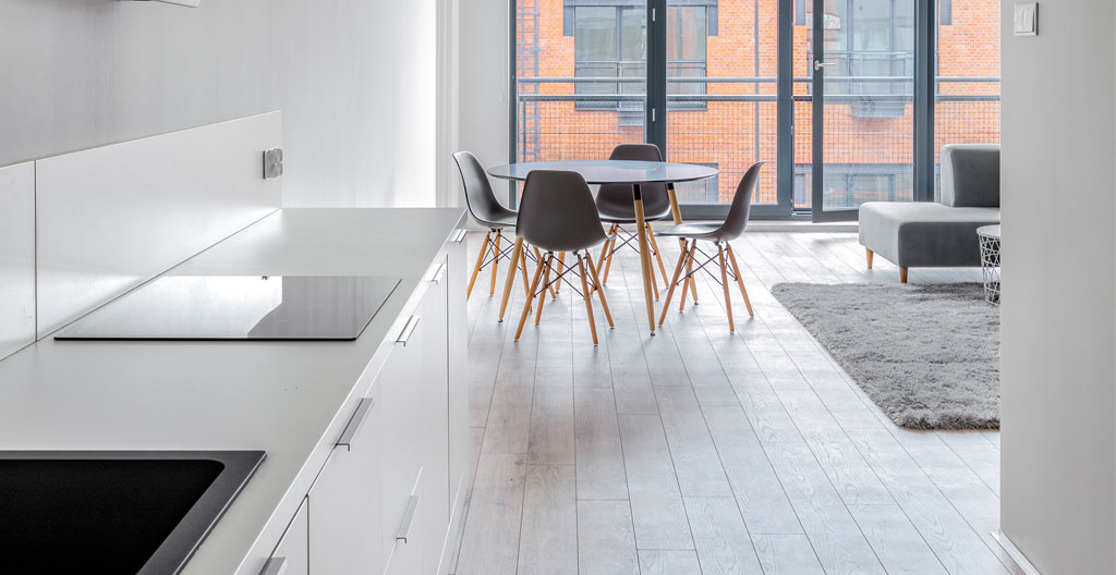 Vue grand angle d'une cuisine ouverte contemporaine française vide avec îlot central et grandes fenêtres apportant une lumière naturelle abondante